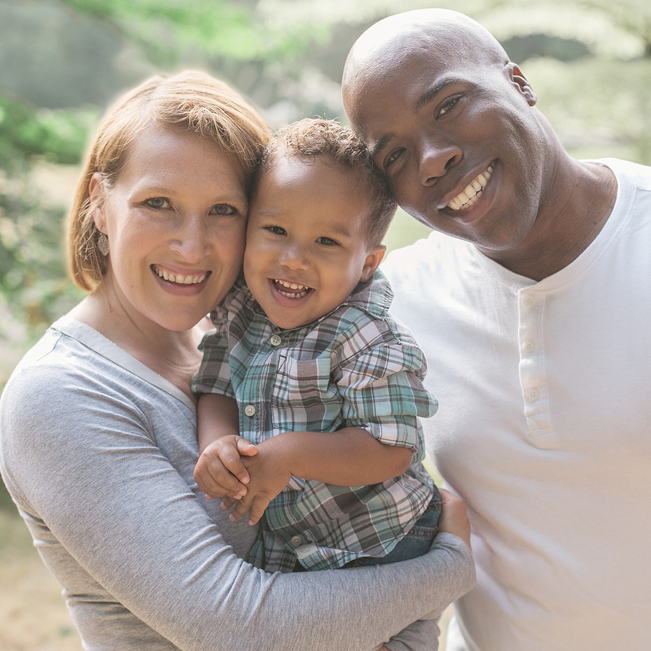 a woman and man holding a baby and smiling