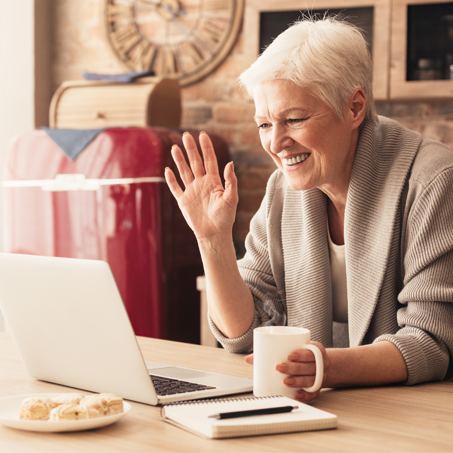 an older woman waving at her computer