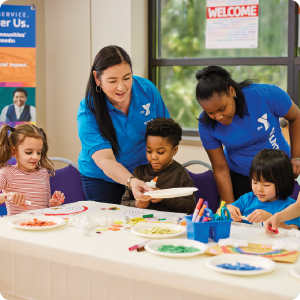 A group of children do an art project assisted by ymca child care staff