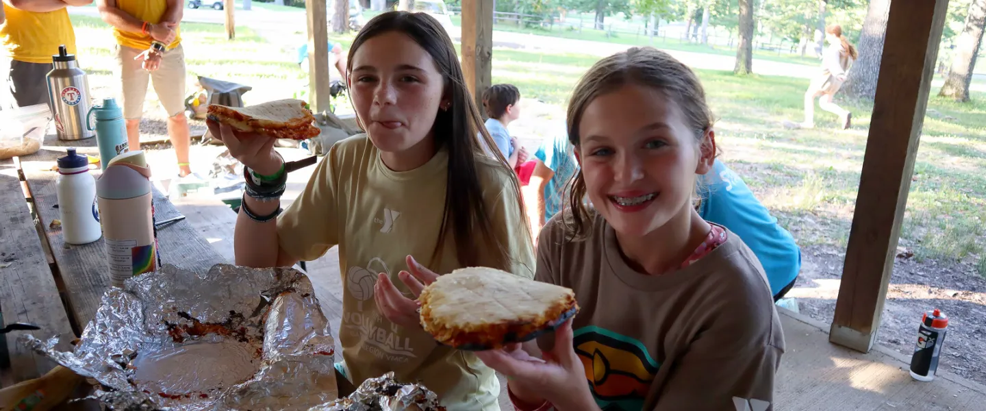 Happy campers enjoying quesadillas wrapped in foil that were cooked over the camp fire