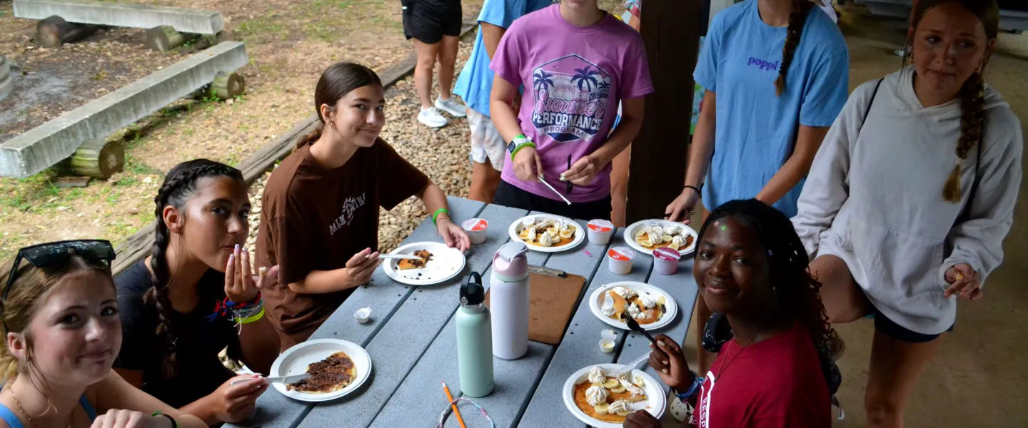 Teen overnight campers at East Camp eating a pancake breakfast with fresh fruit toppings