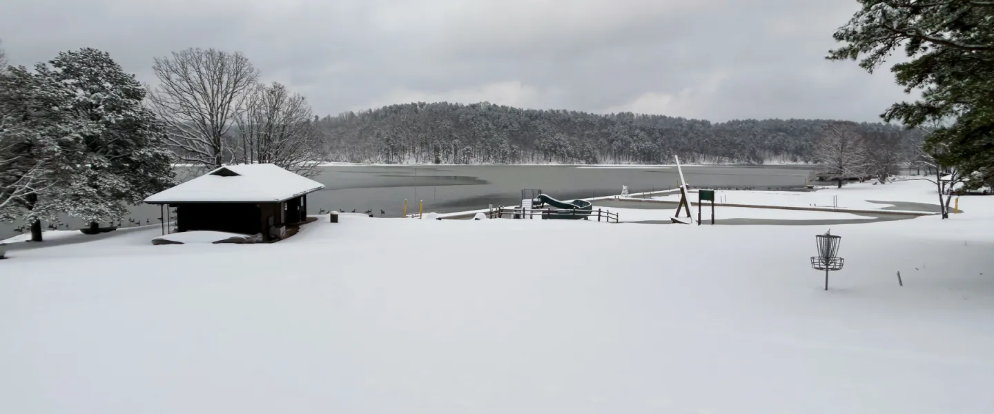 Panoramic view of frozen Sunnen Lake surrounded by snow-covered Ozark hills at YMCA Trout Lodge.