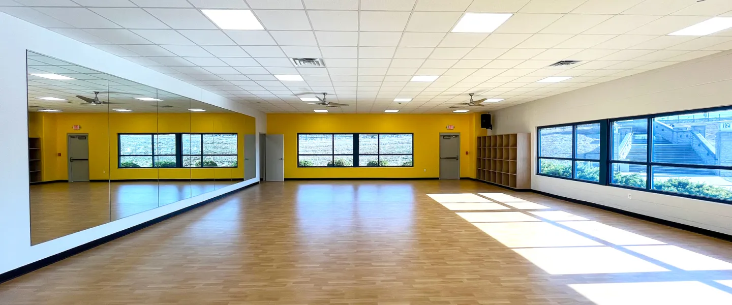 Bright and open group exercise studio at East Belleville YMCA with yellow accent wall and natural lighting for yoga and fitness classes.