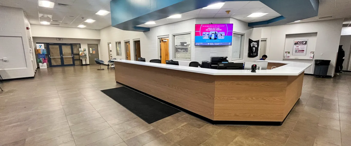 Modern renovated welcome center and front desk at East Belleville YMCA featuring digital signage and an open, accessible lobby area.