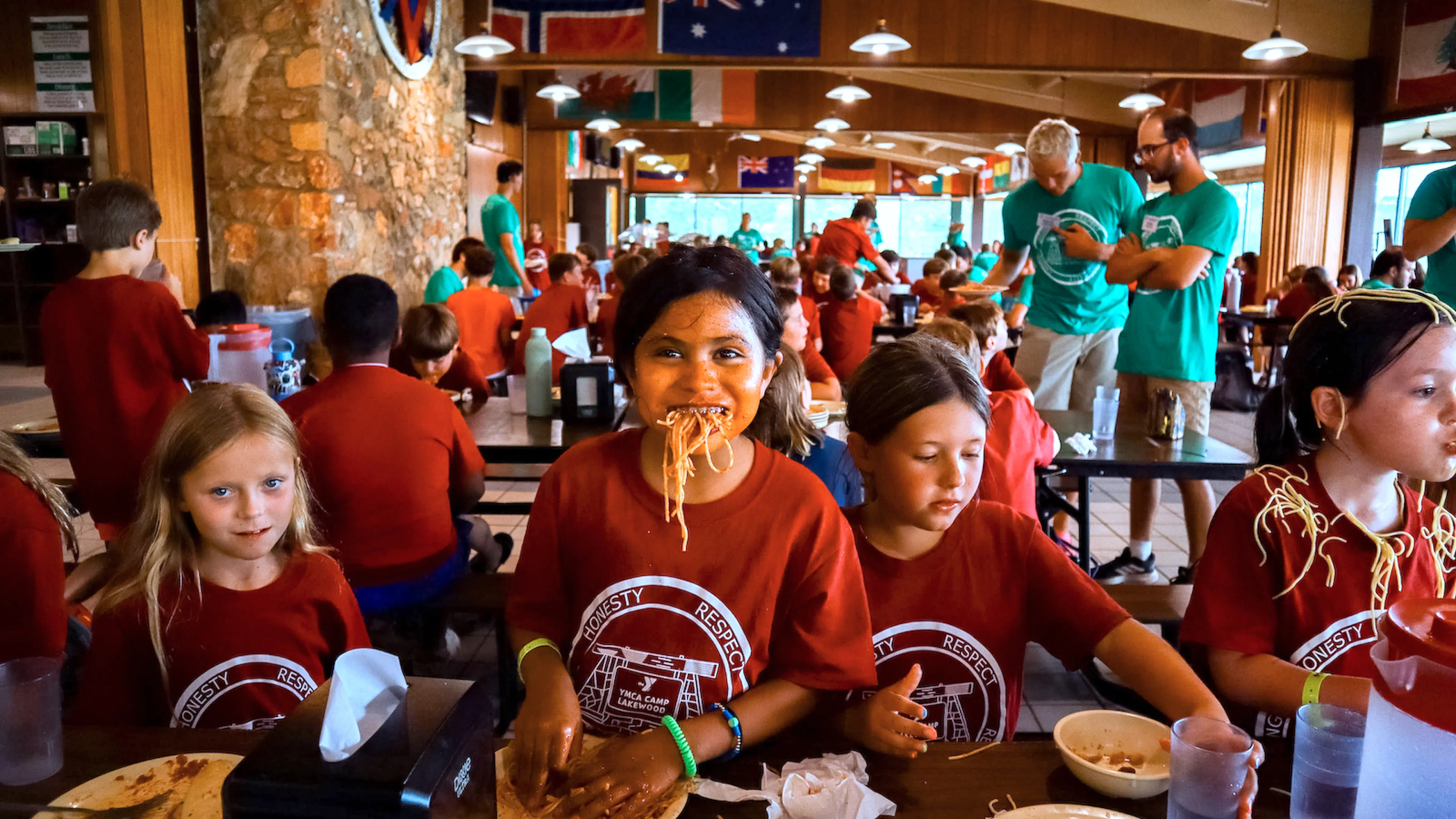 A YMCA Camp Lakewood camper enjoys eating spaghetti with her hands at the famous No Utensils Needed themed dinner.