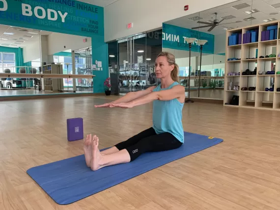 a woman doing a seated forward bend in yoga