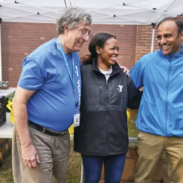 A group of friends smile while having fun at a ymca healthy food distribution event