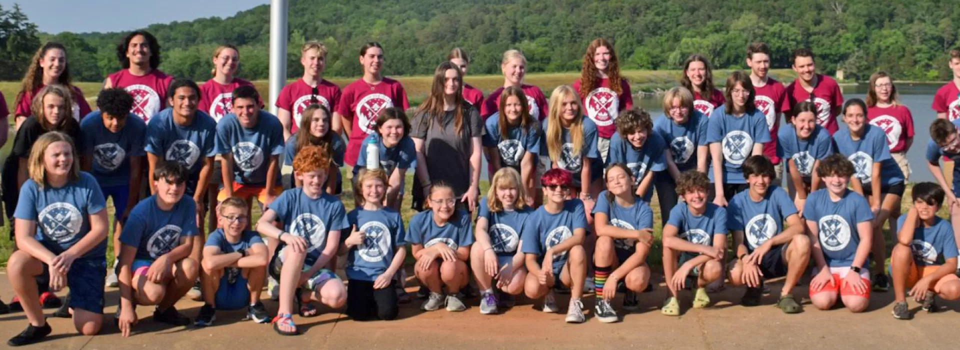 Counselors and campers in camp shirts posing by the lake